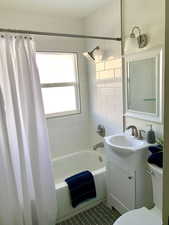 Full bathroom with vanity, shower / bathtub combination with curtain, and toilet