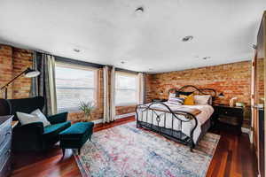 Bedroom featuring brick wall and dark hardwood / wood-style floors