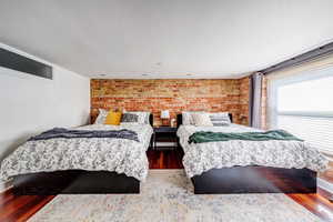 Bedroom featuring hardwood / wood-style floors and brick wall