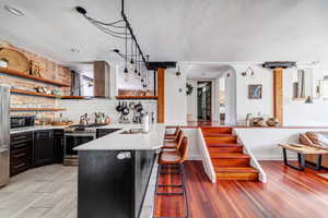 Kitchen featuring kitchen peninsula, stainless steel appliances, sink, pendant lighting, and a breakfast bar area