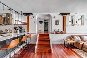 Kitchen with tasteful backsplash, dark hardwood / wood-style flooring, exhaust hood, and a textured ceiling