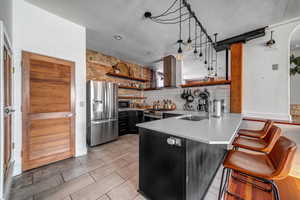 Kitchen featuring a kitchen breakfast bar, sink, decorative light fixtures, kitchen peninsula, and stainless steel appliances