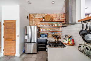 Kitchen featuring decorative backsplash, appliances with stainless steel finishes, and brick wall