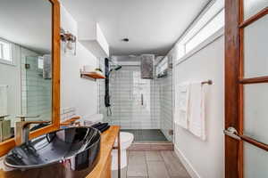 Bathroom featuring toilet, tile patterned floors, a healthy amount of sunlight, and sink