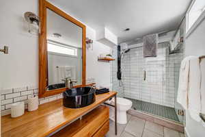 Bathroom with tile patterned flooring, vanity, a shower with door, and toilet