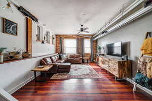 Living room with ceiling fan, a barn door, and dark wood-type flooring