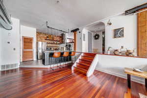 Kitchen with hardwood / wood-style flooring, a kitchen breakfast bar, kitchen peninsula, and stainless steel refrigerator with ice dispenser