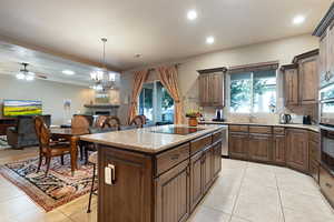 Kitchen with a center island, decorative light fixtures, black electric cooktop, decorative backsplash, and ceiling fan with notable chandelier