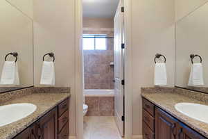 Bathroom featuring toilet, vanity, a relaxing tiled tub, and tile patterned floors