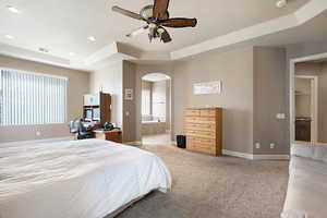 Bedroom with ceiling fan, light carpet, connected bathroom, and a tray ceiling