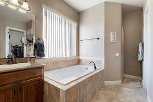 Bathroom with tile patterned floors, vanity, and tiled tub