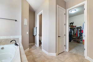 Bathroom featuring tile patterned floors, toilet, and a tub