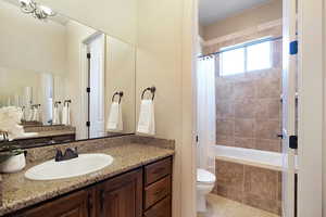 Full bathroom featuring shower / bathtub combination with curtain, an inviting chandelier, tile patterned flooring, toilet, and vanity