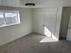 Unfurnished bedroom with a closet, carpet floors, and a textured ceiling