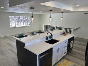 Kitchen featuring white cabinets, sink, hanging light fixtures, and a kitchen island with sink