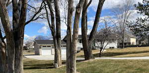 View of front of property featuring a mountain view, a front yard, and a garage