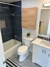 Full bathroom featuring toilet, tile patterned flooring, vanity, and tiled shower / bath