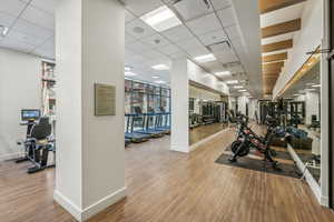 Workout area with a paneled ceiling and wood-type flooring