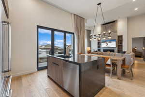 Kitchen featuring sink, hanging light fixtures, light hardwood / wood-style floors, a fireplace, and a center island with sink