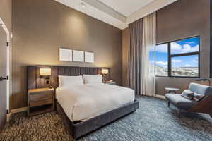 Bedroom with a towering ceiling and dark carpet