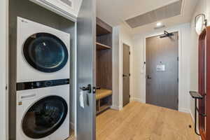 Laundry area featuring light hardwood / wood-style floors and stacked washer and clothes dryer