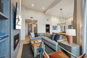 Living room featuring a fireplace, light hardwood / wood-style flooring, and a towering ceiling