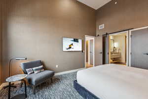 Bedroom featuring ensuite bath, sink, a towering ceiling, and a barn door