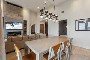 Dining space featuring light wood-type flooring, a fireplace, and high vaulted ceiling