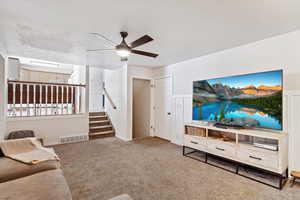 Carpeted living room featuring ceiling fan