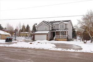 View of property with covered porch, central AC unit, and a garage