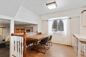 Dining space with light hardwood / wood-style flooring and lofted ceiling