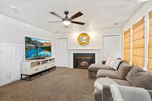 Carpeted living room with ceiling fan and a fireplace