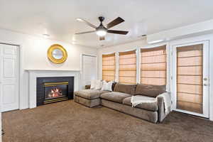 Living room with ceiling fan, a fireplace, and carpet floors