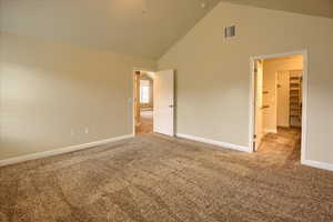 Unfurnished bedroom with carpet, a walk in closet, high vaulted ceiling, and a closet