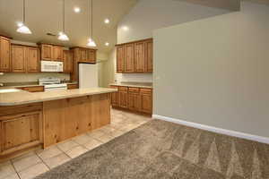 Kitchen featuring white appliances, sink, light tile patterned floors, high vaulted ceiling, and hanging light fixtures