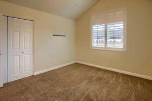 Carpeted spare room with vaulted ceiling