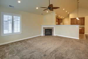 Unfurnished living room with a tile fireplace, ceiling fan, high vaulted ceiling, and light carpet