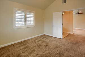 Carpeted spare room with ceiling fan and lofted ceiling