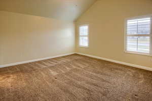 Unfurnished room featuring carpet flooring, a wealth of natural light, and vaulted ceiling