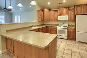 Kitchen featuring sink, hanging light fixtures, kitchen peninsula, white appliances, and light tile patterned floors