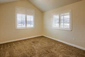 Empty room featuring carpet and lofted ceiling