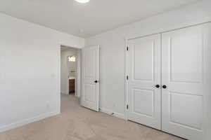 Unfurnished bedroom featuring light carpet and a closet