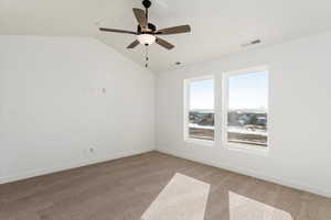 Carpeted spare room featuring ceiling fan and vaulted ceiling