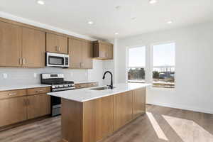 Kitchen with an island with sink, stainless steel appliances, hardwood / wood-style flooring, and sink