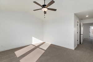 Spare room with carpet flooring, ceiling fan, and vaulted ceiling