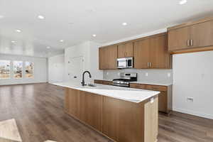 Kitchen with decorative backsplash, appliances with stainless steel finishes, a center island with sink, and sink