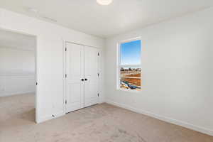 Unfurnished bedroom with light carpet and a closet