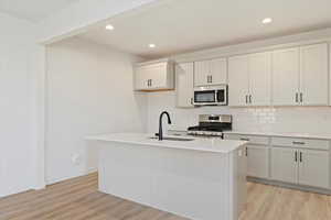 Kitchen featuring a center island with sink, light hardwood / wood-style flooring, stainless steel appliances, and sink