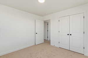 Unfurnished bedroom with light colored carpet and a closet