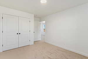 Unfurnished bedroom featuring light carpet and a closet